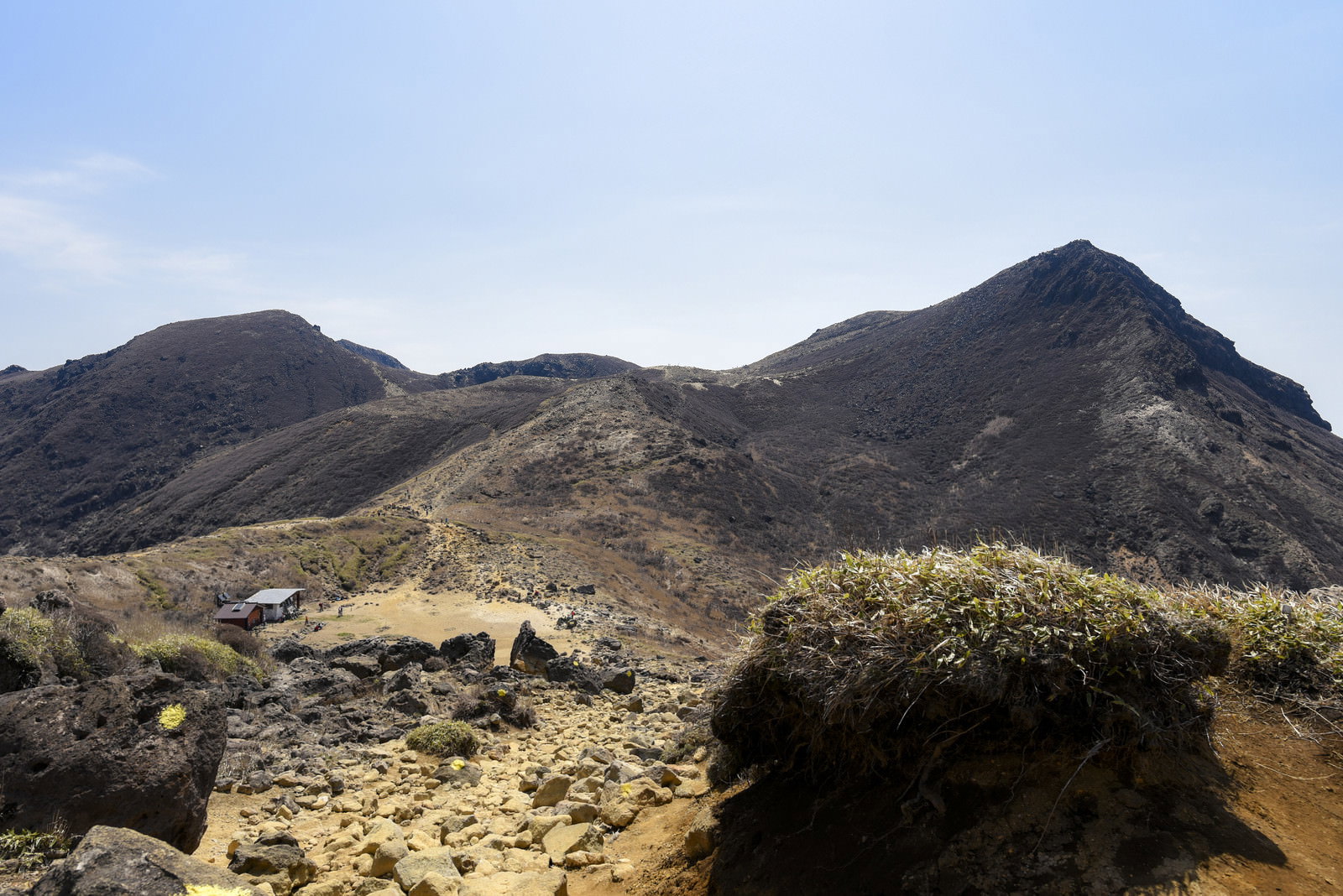 久住山山頂付近の荒涼とした火山地形に建つ避難小屋と背景の山々