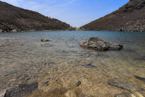 久住山御池に積み重なった岩と真っ青な水、火山湖の景観（大分県）