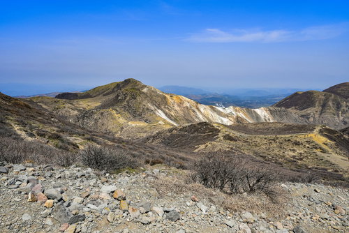 岩と枯れ木が点在する春の久住山、100名山の火山地帯