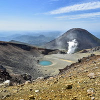 噴煙が上がる雌阿寒岳と青池の北海道の山岳風景の写真