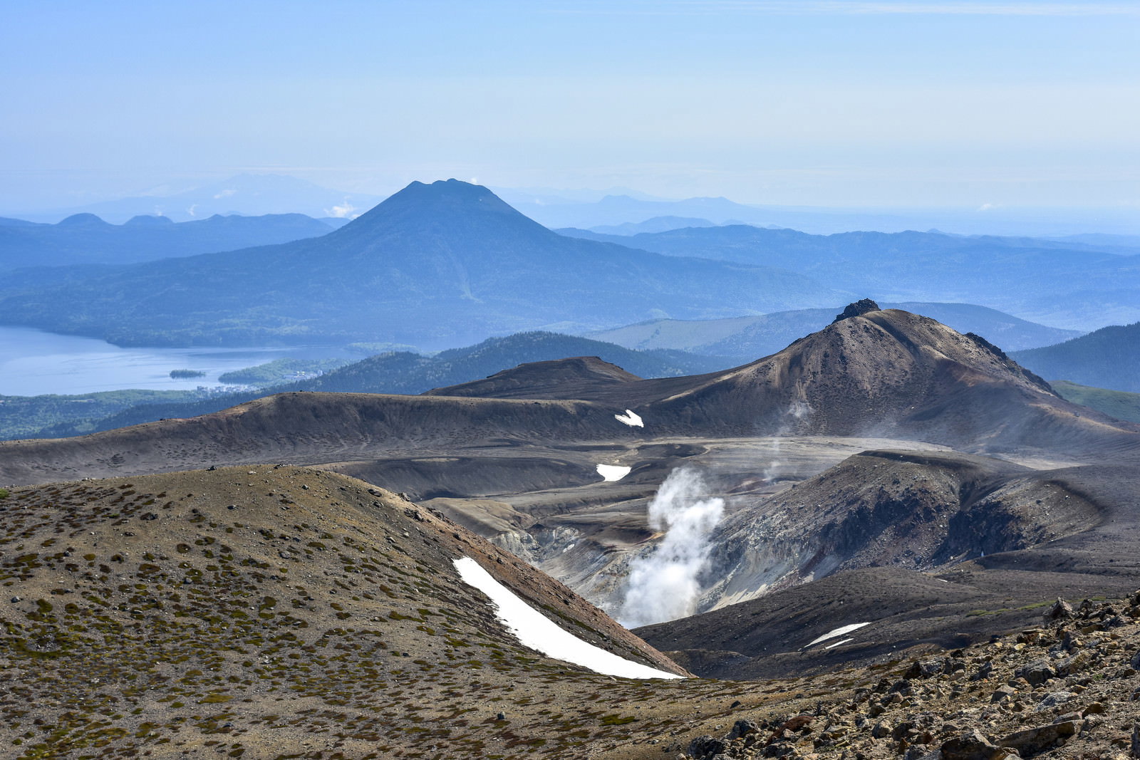 噴煙を上げる雌阿寒岳の火山性大地を捉えた山岳風景