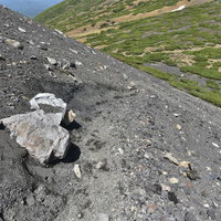 雌阿寒岳・阿寒富士中腹の砂礫登山道を行く登山者の風景の写真