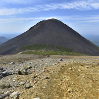 雌阿寒岳の岩場から見る円錐形の阿寒富士と荒野の絶景の写真
