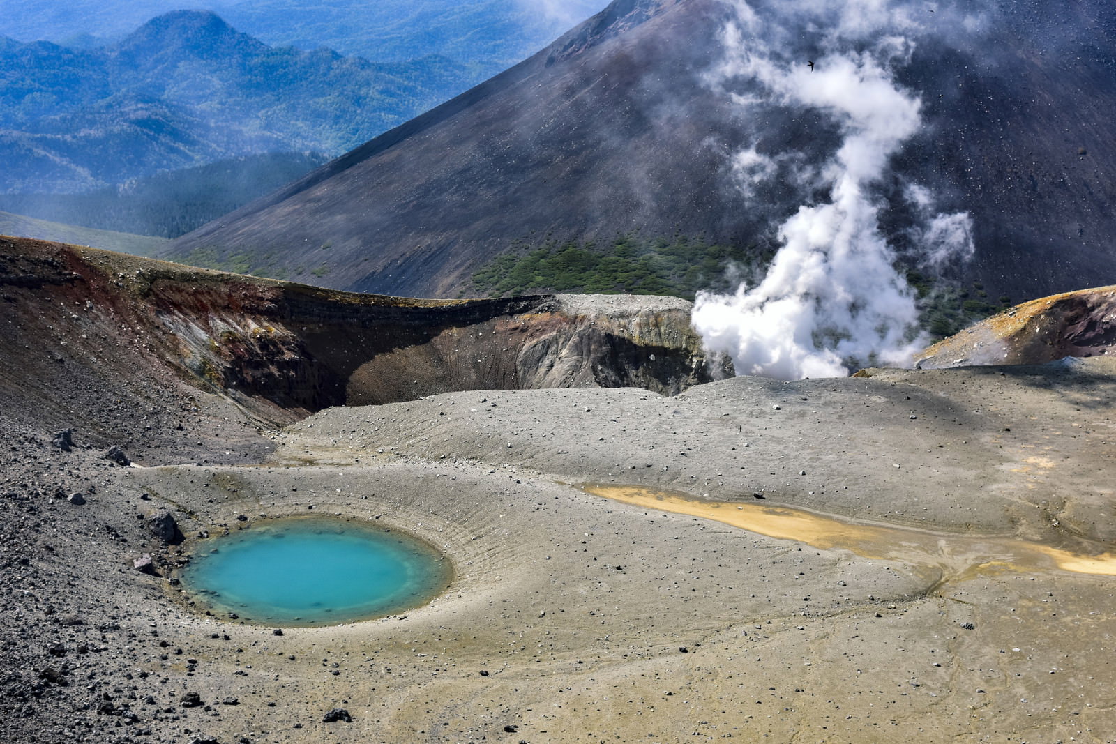 雌阿寒岳の青池と火山地形の風景