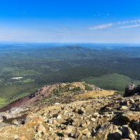 雌阿寒岳中腹の岩場から見る北の原生林と青空の写真