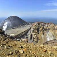 雌阿寒岳の火口と背後に聳える阿寒富士の雄大な火山風景の写真