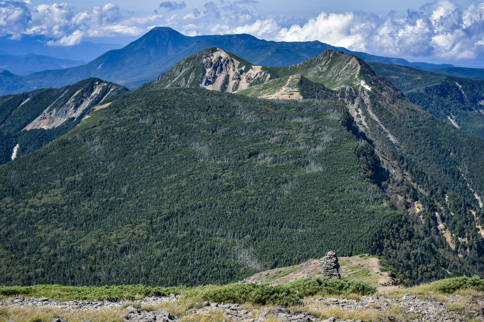 横岳から見た北八ヶ岳方面の山並み、緑の山々と青空が広がる山岳風景