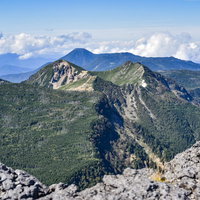赤岳から見た横岳の奥に広がる蓼科山方面の山並みの写真