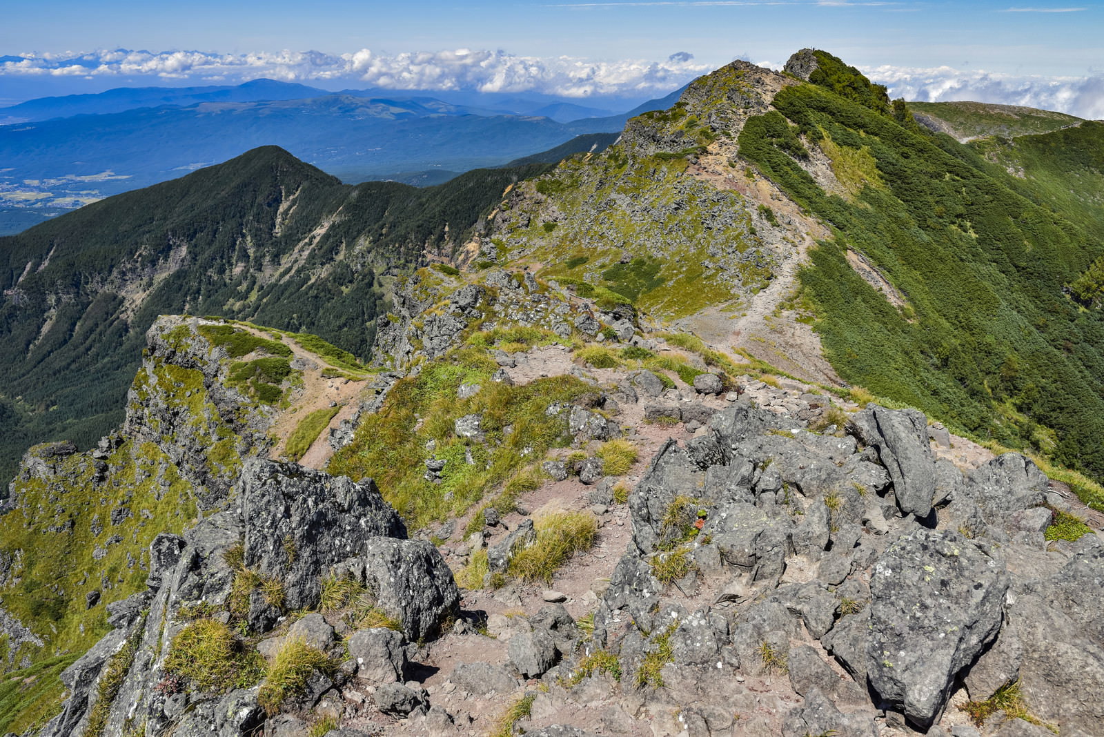 硫黄岳へ向かう横岳の稜線。緑の草原と岩場が続く登山道