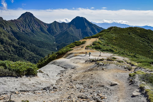 赤岳を背景に硫黄岳の稜線を登る登山者たち