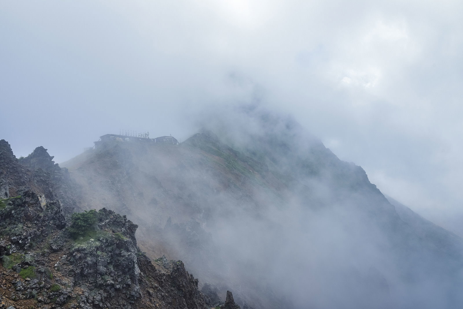 ガスに包まれた山々の中にうっすらと見える山小屋