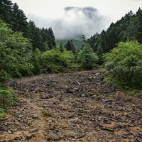 雲の中へと進む八ヶ岳赤岳の登山道、岩場を歩む登山者の写真