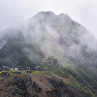 雲を纏う赤岳（あかだけ）と山小屋の写真