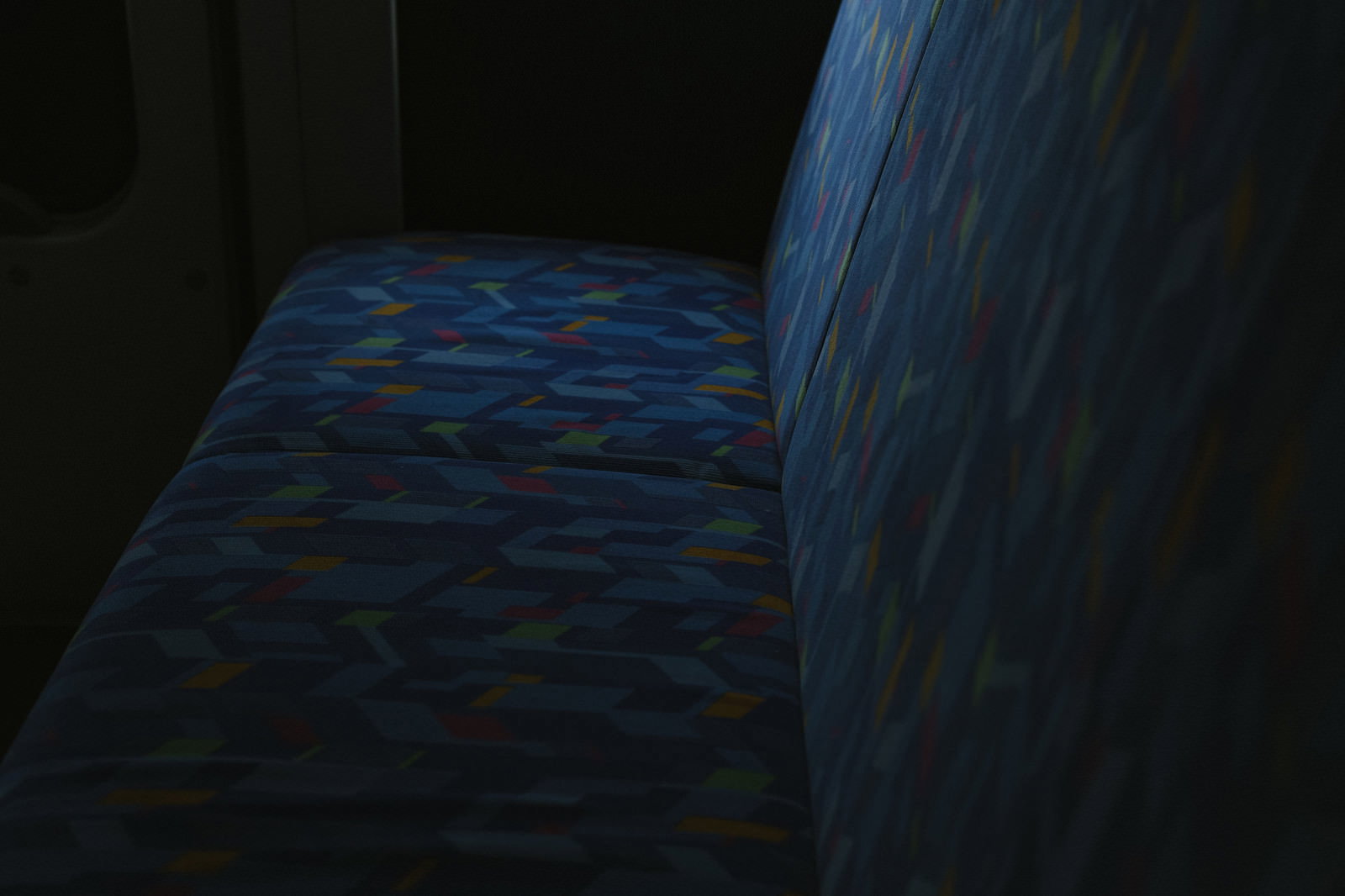薄暗い青い光に照らされたバスの座席が並ぶ車内