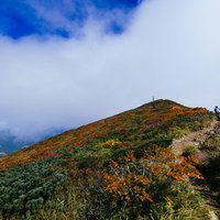 雲の合間に見える栗駒山の秋の紅葉と青空の風景の写真