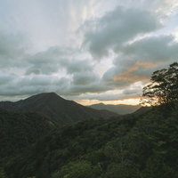 雲の隙間から覗く朝焼けと緑深き山々の朝日風景の写真
