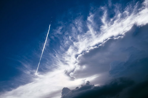 青空に立ち上がるかなとこ雲のそばを飛んで行く飛行機雲