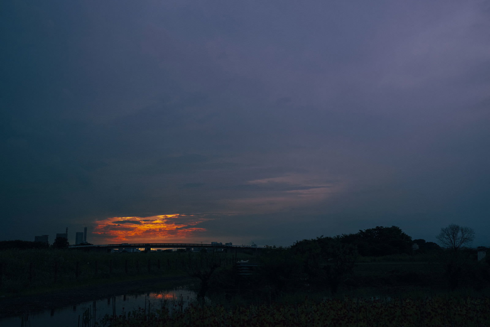 夕日を雲が包み込むように広がる夕焼け空とシルエットの風景