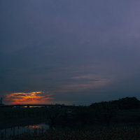 夕日を包み込むように広がる雲の空とシルエットの風景の写真