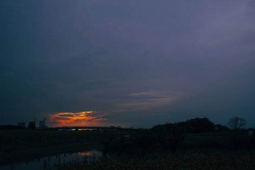 夕日を包み込むように広がる雲の空とシルエットの風景