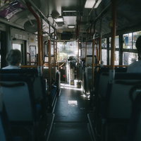 早朝の薄暗い通勤バスの車内、青緑色シートと静寂の空間の写真
