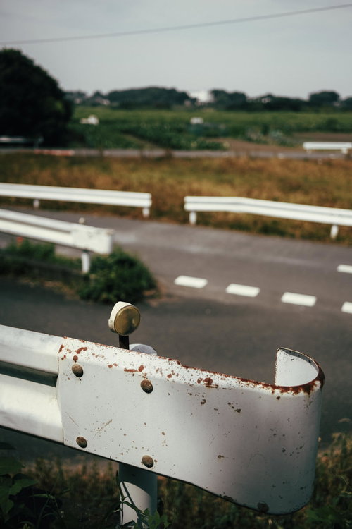 白いペンキが剥がれた昭和な錆びたガードレール