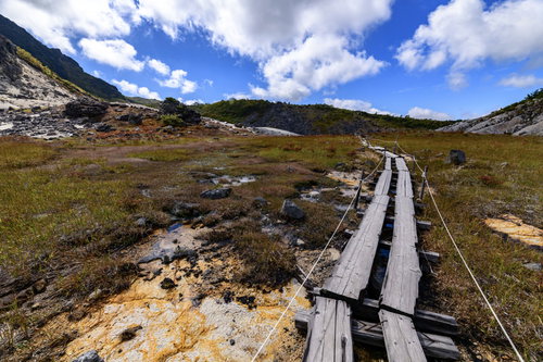 栗駒山の火山性の大地の上に通された木道と火山岩