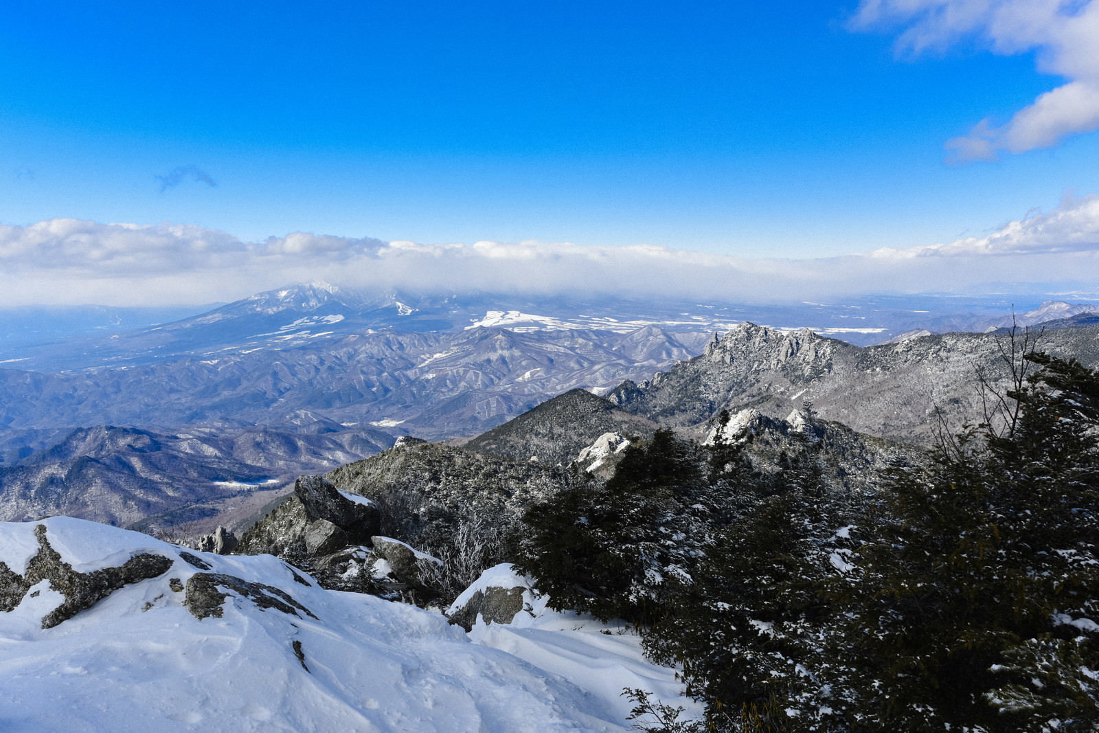 金峰山から見た雪化粧の瑞牆山と雲に覆われた八ヶ岳の冬景色