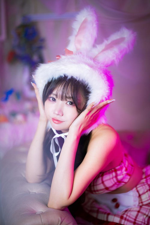 ピンク照明の中でにっこり笑うバニートラップ姿の女性