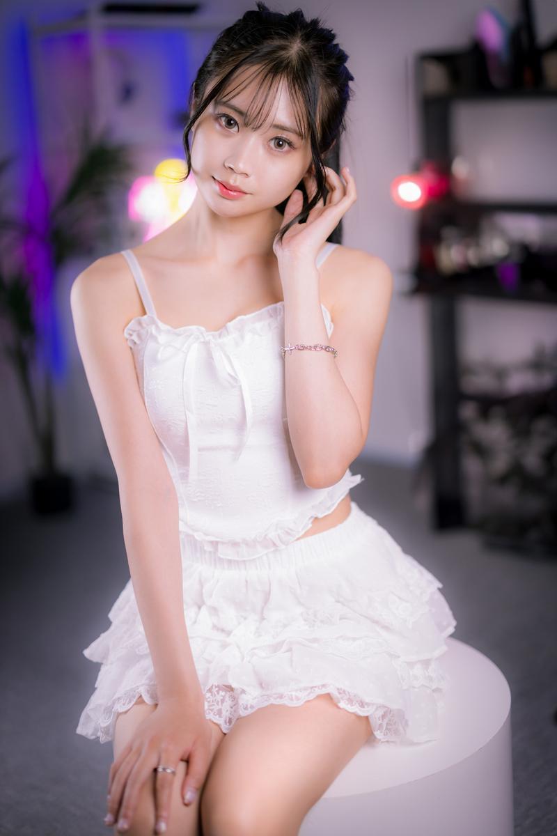 ネオンライトが光る室内で白いドレス姿のゲーミング女子がカメラを見つめる［モデル：れいか氏］
