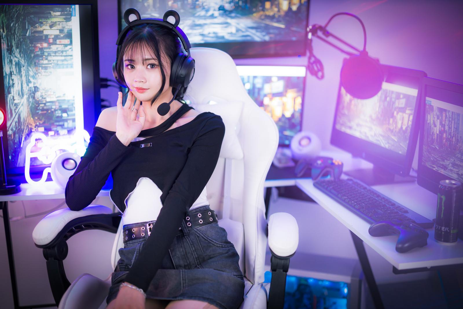 マルチディスプレイ環境でゲームをするゲーミング女子がヘッドセットを装着して座っている［モデル：れいか氏］