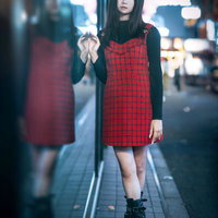 夜の繁華街でガラスに寄りかかる女性のポートレートの写真