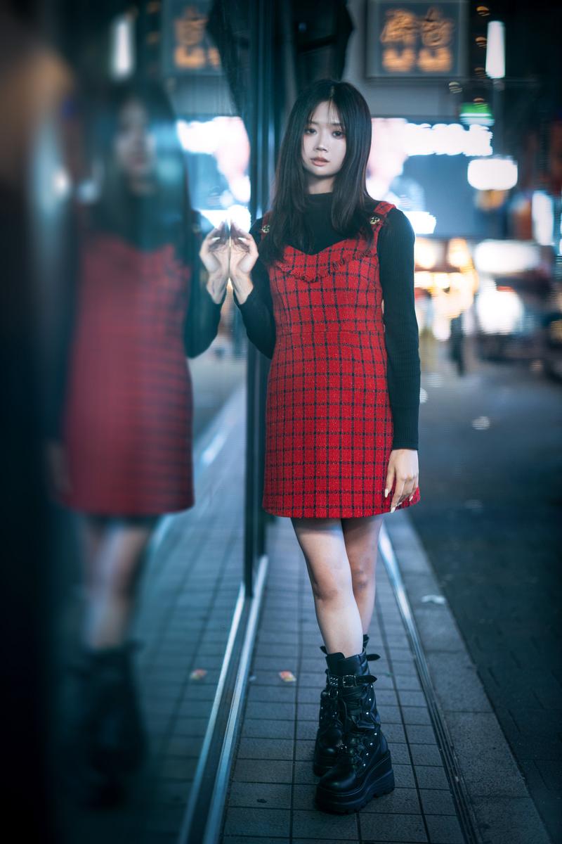 Woman leaning against glass in a nighttime city district