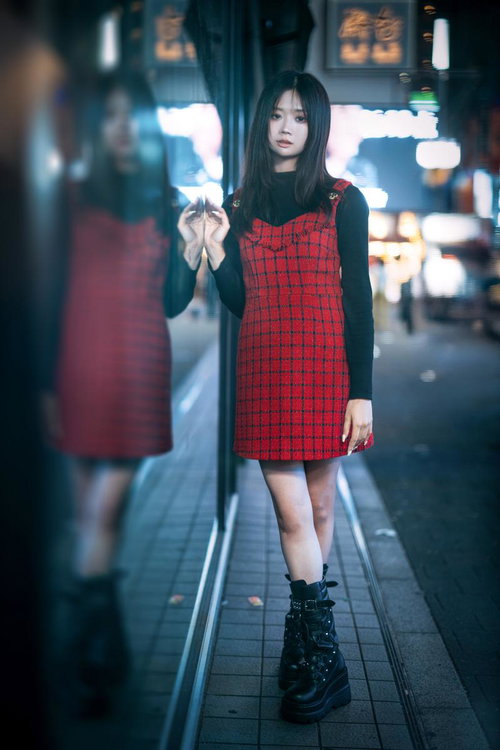 夜間の新宿で赤いチェック柄ワンピースと黒いブーツを着た女性のポートレート