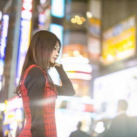 繁華街のネオンを背景にした女性のポートレートの写真