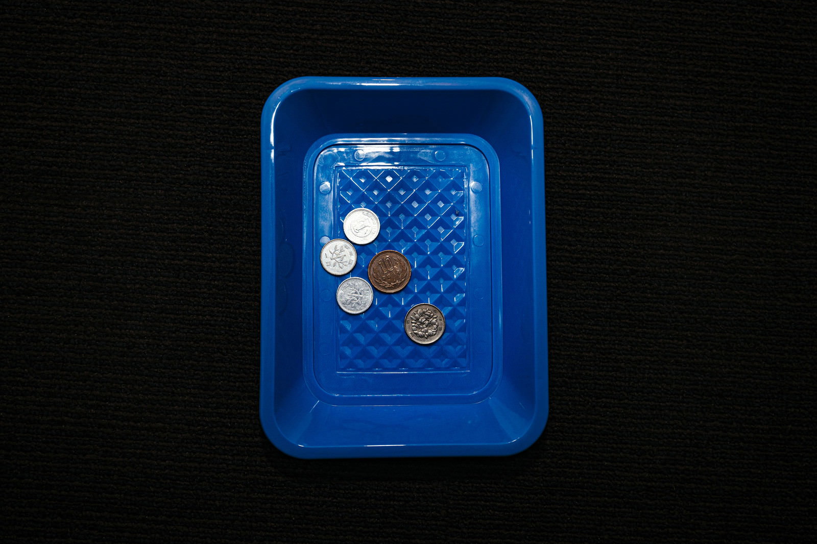 青いプラスチックトレーに1円玉、5円玉、10円玉が置かれた18円のお釣り