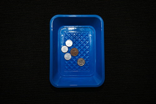 青いトレーに置かれたお釣り18円の硬貨。1円玉5円玉10円玉の内訳