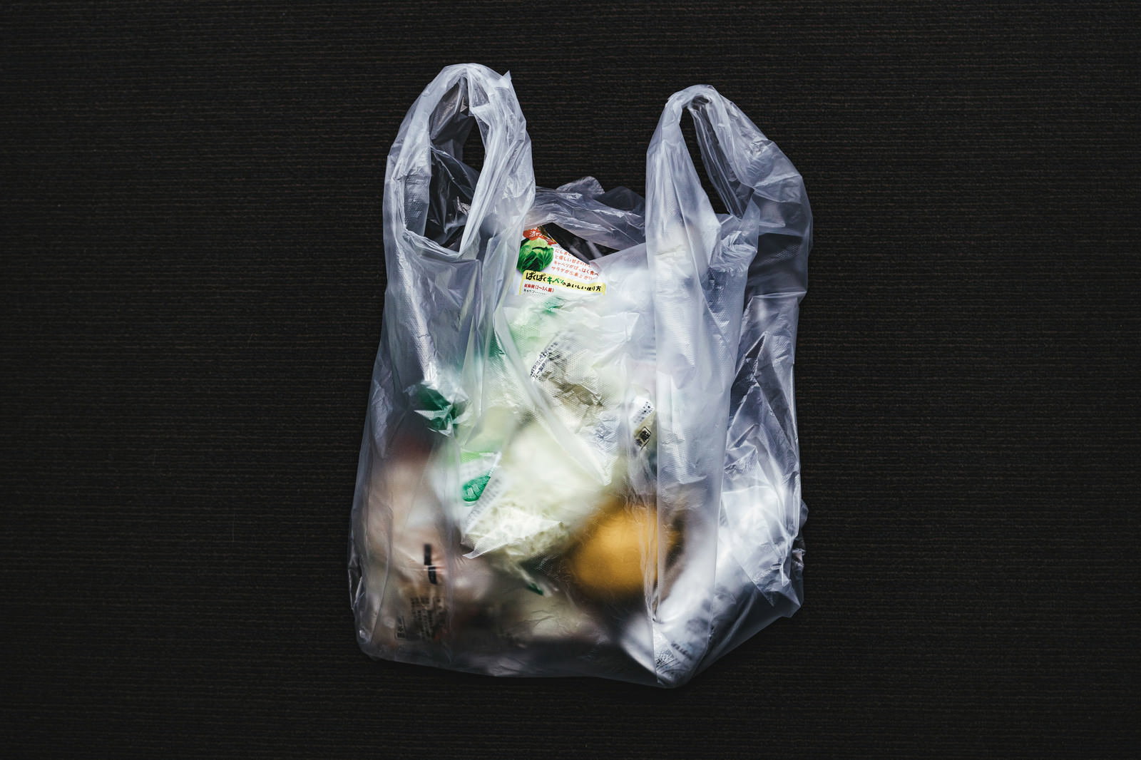 白いレジ袋に食品や商品を詰めている買い物の様子