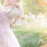淡いピンクのワンピース姿で木漏れ日に包まれる森ガール女性の写真