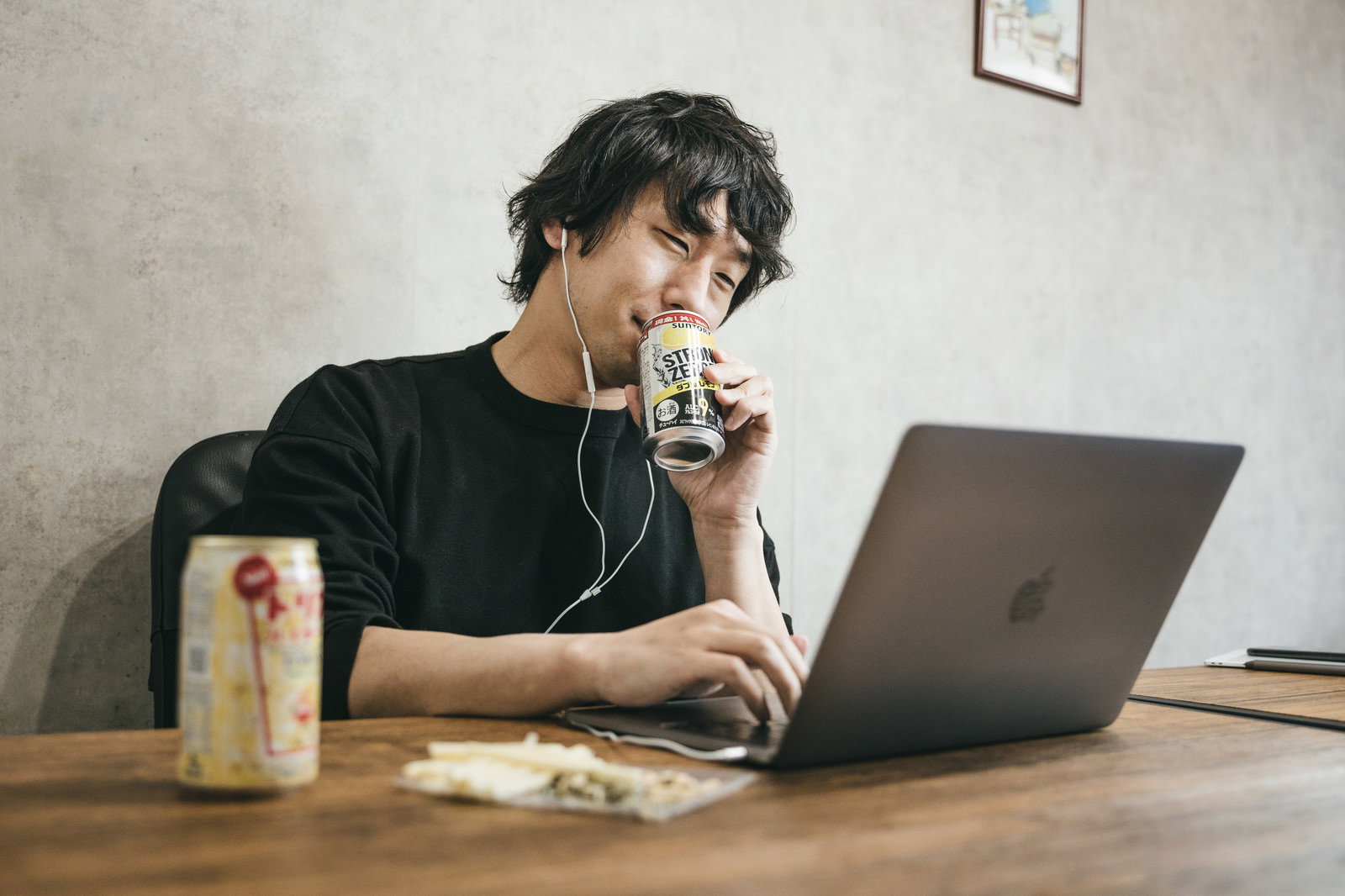 木製デスクで缶チューハイを飲みながらノートパソコンで作業する男性［モデル：大川竜弥］