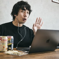 ノートパソコンでリモート飲みをする同窓会の男性の写真