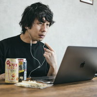 声聞こえてる？リモート飲み会中の男性とパソコンとイヤホンの写真