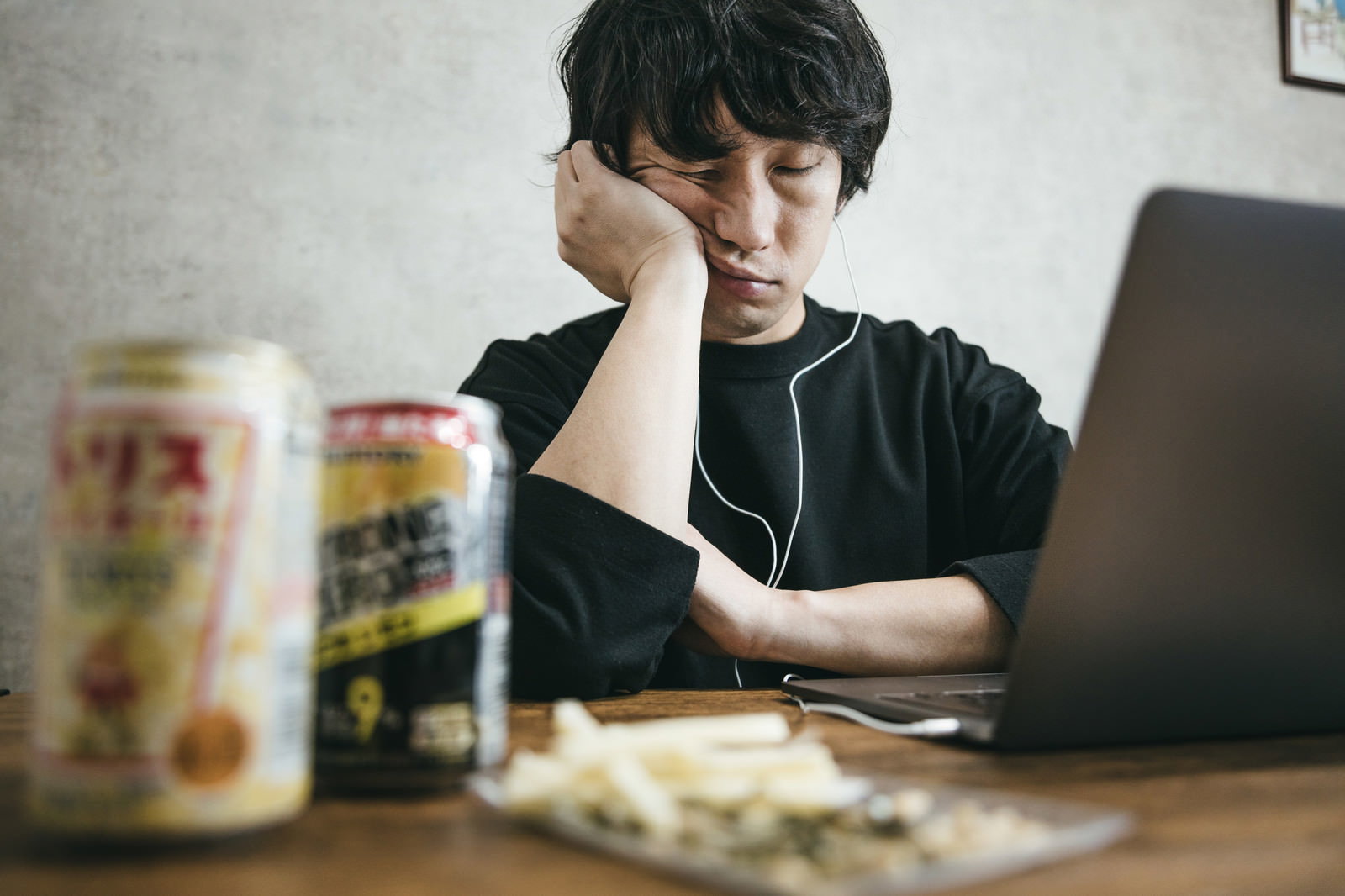 パソコンの前で頬杖をついて眠る男性とストロングゼロの缶［モデル：大川竜弥］