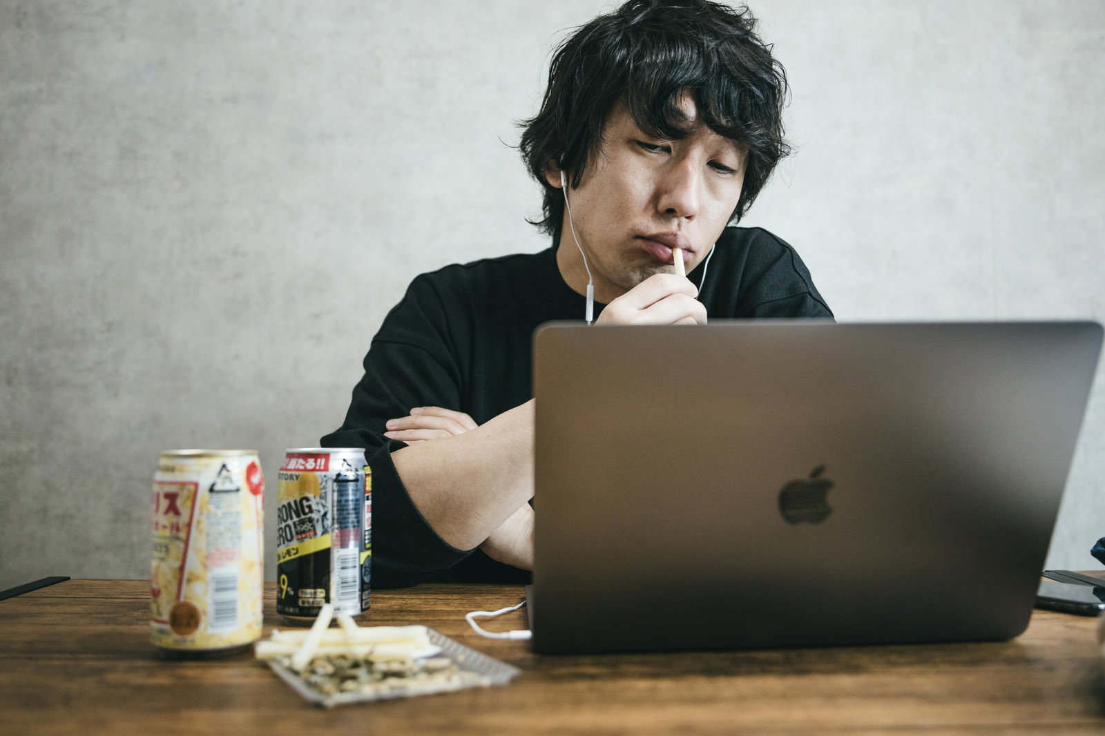 パソコンの前でストロングゼロを手に不満げな表情を浮かべる男性［モデル：大川竜弥］