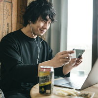 リモート飲みの画面をスマホで撮る男性のテレワーク風景の写真