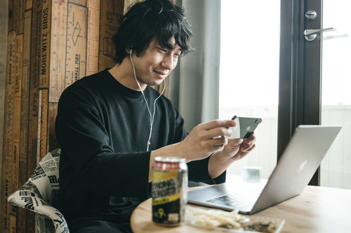 リモート飲みの画面をスマホで撮る男性のテレワーク風景