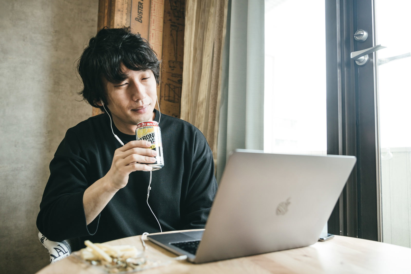 ノートパソコンの前で缶チューハイを持ちリモート飲み中に困惑する男性［モデル：大川竜弥］