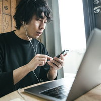 作業中にニュースアプリをチェックする男性リモートワーカーの写真