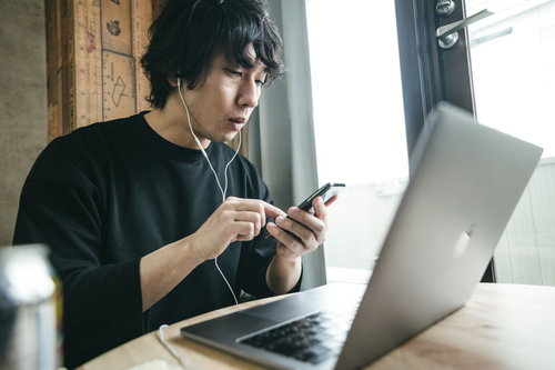 作業中にニュースアプリをチェックする男性リモートワーカー