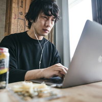 終業10分前、デスクでおつまみとストロングゼロを前に仕事を続ける男性の写真